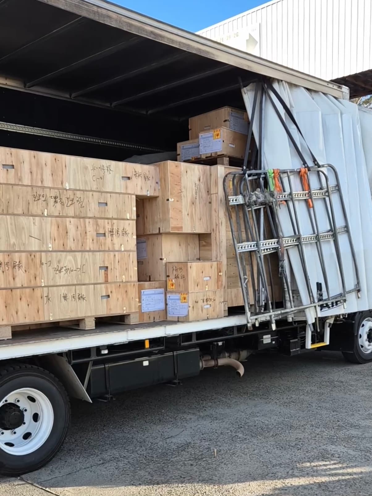 Wooden shipping crates stacked inside an open-sided truck, ready for transport and delivery.